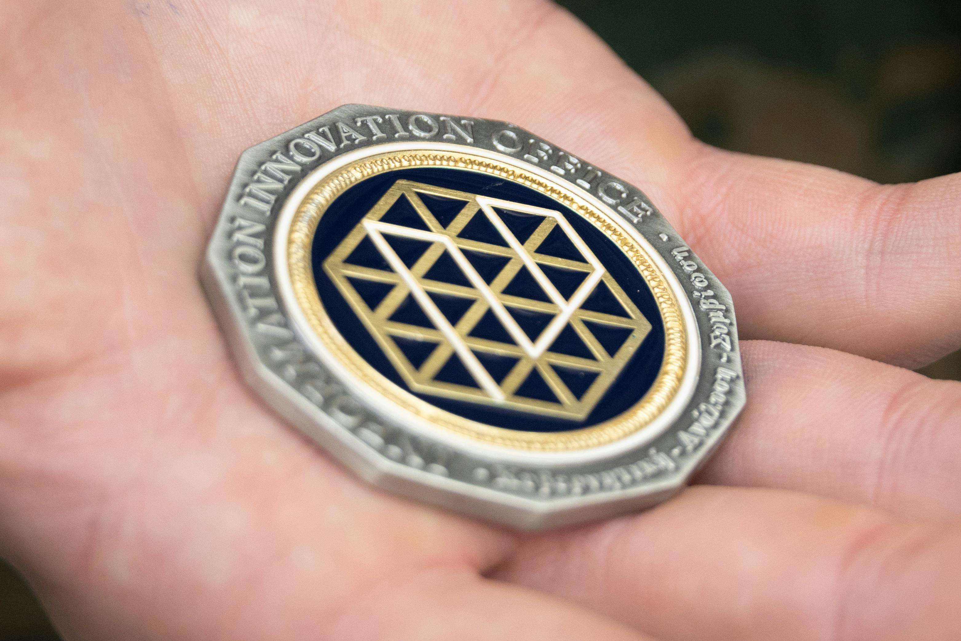 A U.S. Marine holds a Defense Advanced Research Projects Agency Information Innovation Office challenge coin after receiving it on Camp Hansen, Okinawa, Japan. U.S. Marine Corps photo by Lance Cpl. Christopher R. Lape.