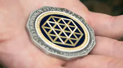 A U.S. Marine holds a Defense Advanced Research Projects Agency Information Innovation Office challenge coin after receiving it on Camp Hansen, Okinawa, Japan. U.S. Marine Corps photo by Lance Cpl. Christopher R. Lape.