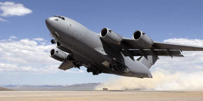 A C-17 takes off from a dusty runway