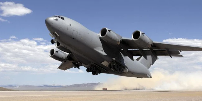 A C-17 takes off from a dusty runway