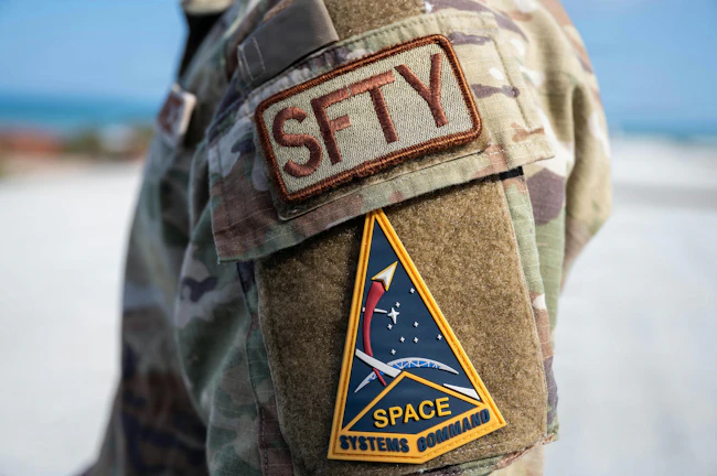 A close-up of the safety identifier patch and Space Systems Command insignia worn by U.S. Air Force Tech. U.S. Air Force photo by Staff Sgt. Samuel Becker.