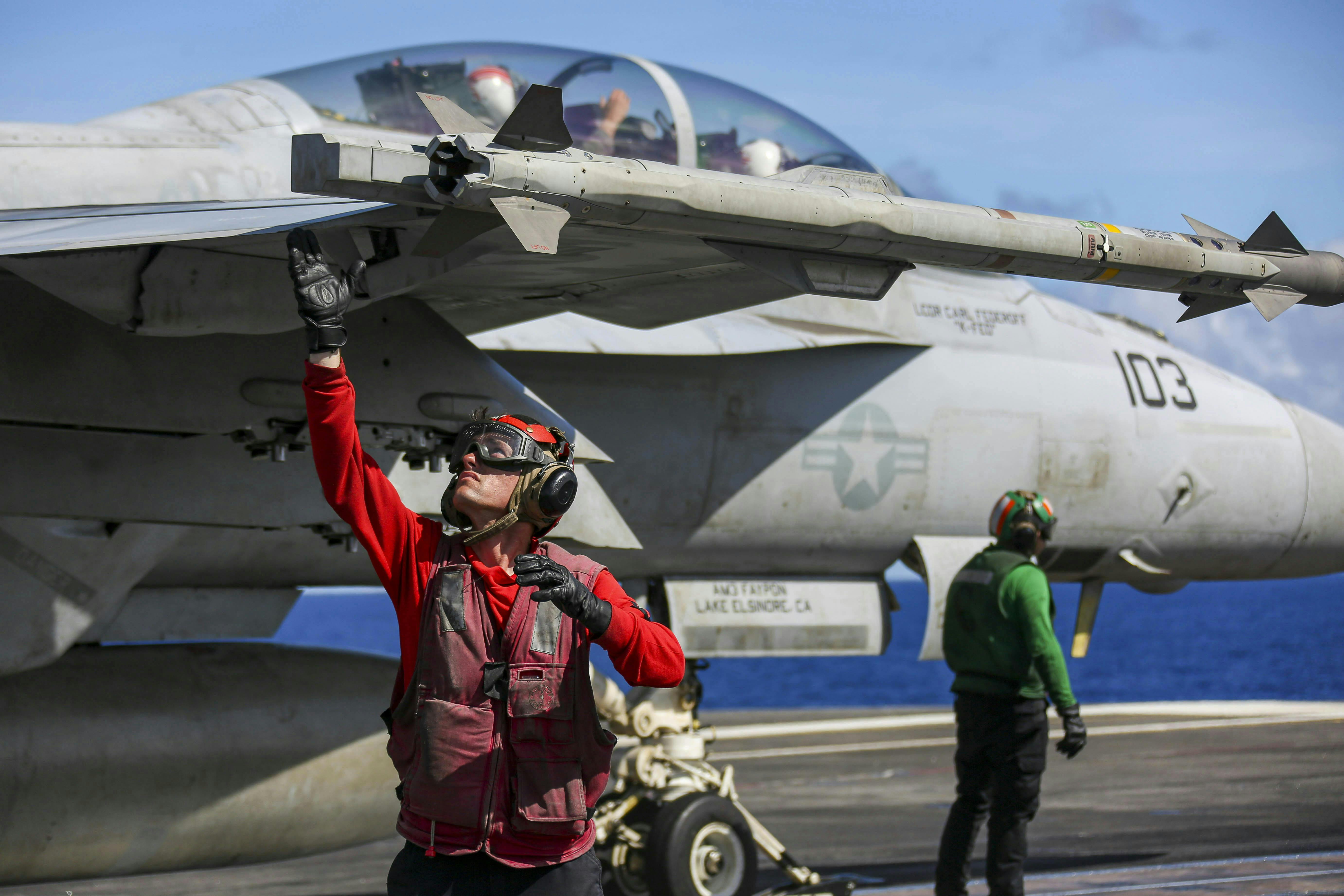 A Navy aviation ordnanceman arms up an AIM-9X missile on an F/A-18F Super Hornet on the flight deck of the Nimitz-class aircraft carrier USS Abraham Lincoln (CVN 72). U.S. Navy photo.