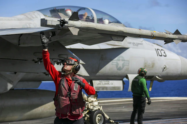 A Navy aviation ordnanceman arms up an AIM-9X missile on an F/A-18F Super Hornet on the flight deck of the Nimitz-class aircraft carrier USS Abraham Lincoln (CVN 72). U.S. Navy photo.