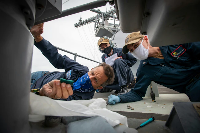 Naval Surface Warfare Center, Port Hueneme Division (NSWC PHD) Engineer Andre Casanave works with Fire Controlman Petty Officer 1st Class Lindsey Presley and Fire Controlman Petty Officer 3rd Class Edward Kuchman on maintaining the Mark (MK) 46 Optical Sight System (OSS) for the MK 34 deck gun aboard USS Chafee (DDG 90) while in port at NSWC PHD. U.S. Navy Photo by Eric Parsons.