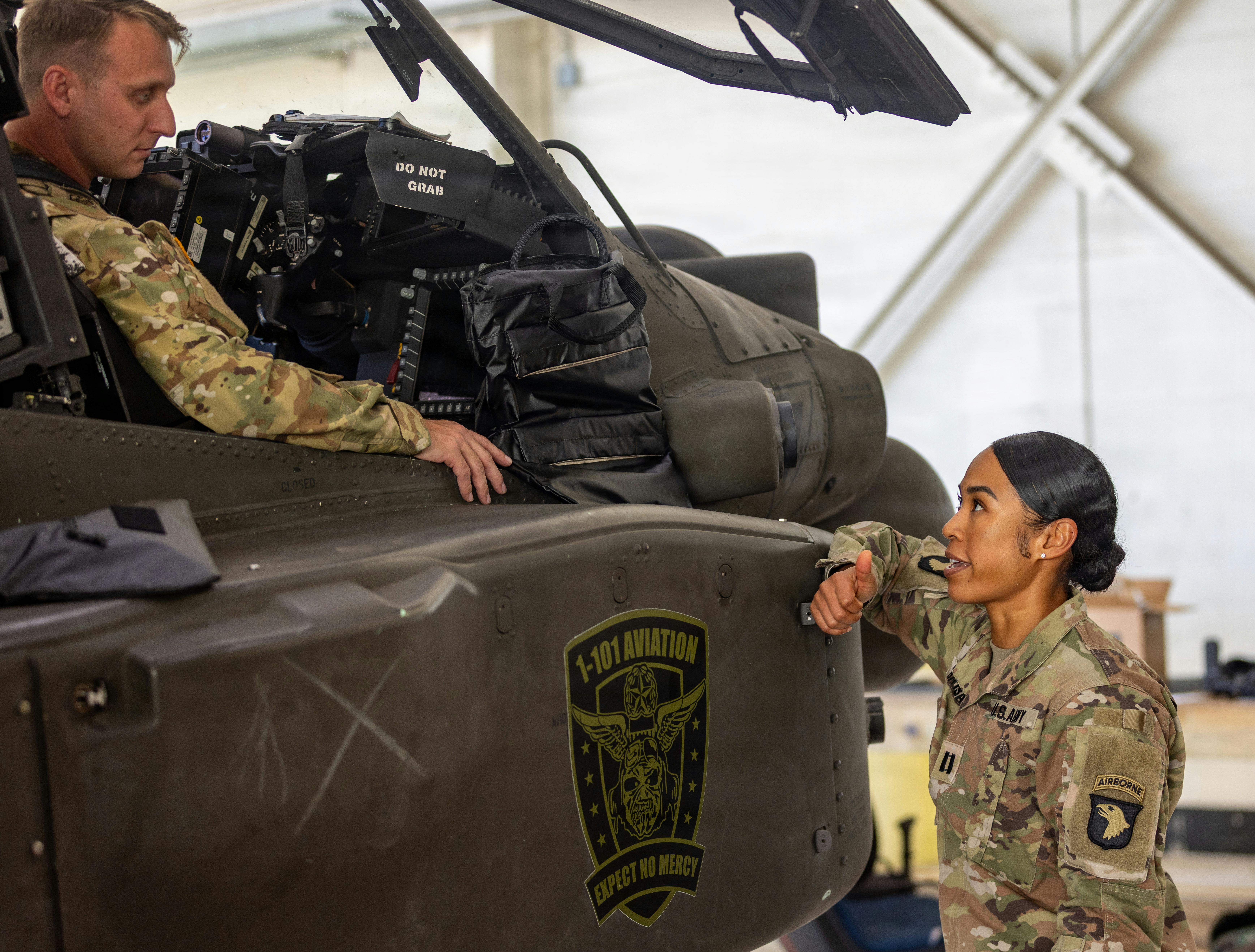 Capt. Gena Baisa, 101st Combat Aviation Brigade dietitian, speaks with Chief Warrant Officer 2 Jeremy Howell, a 101st CAB pilot, as he sits in the cockpit of an AH-64 Apache helicopter. U.S. Army photo by Capt. Andrew Lightsey IV.