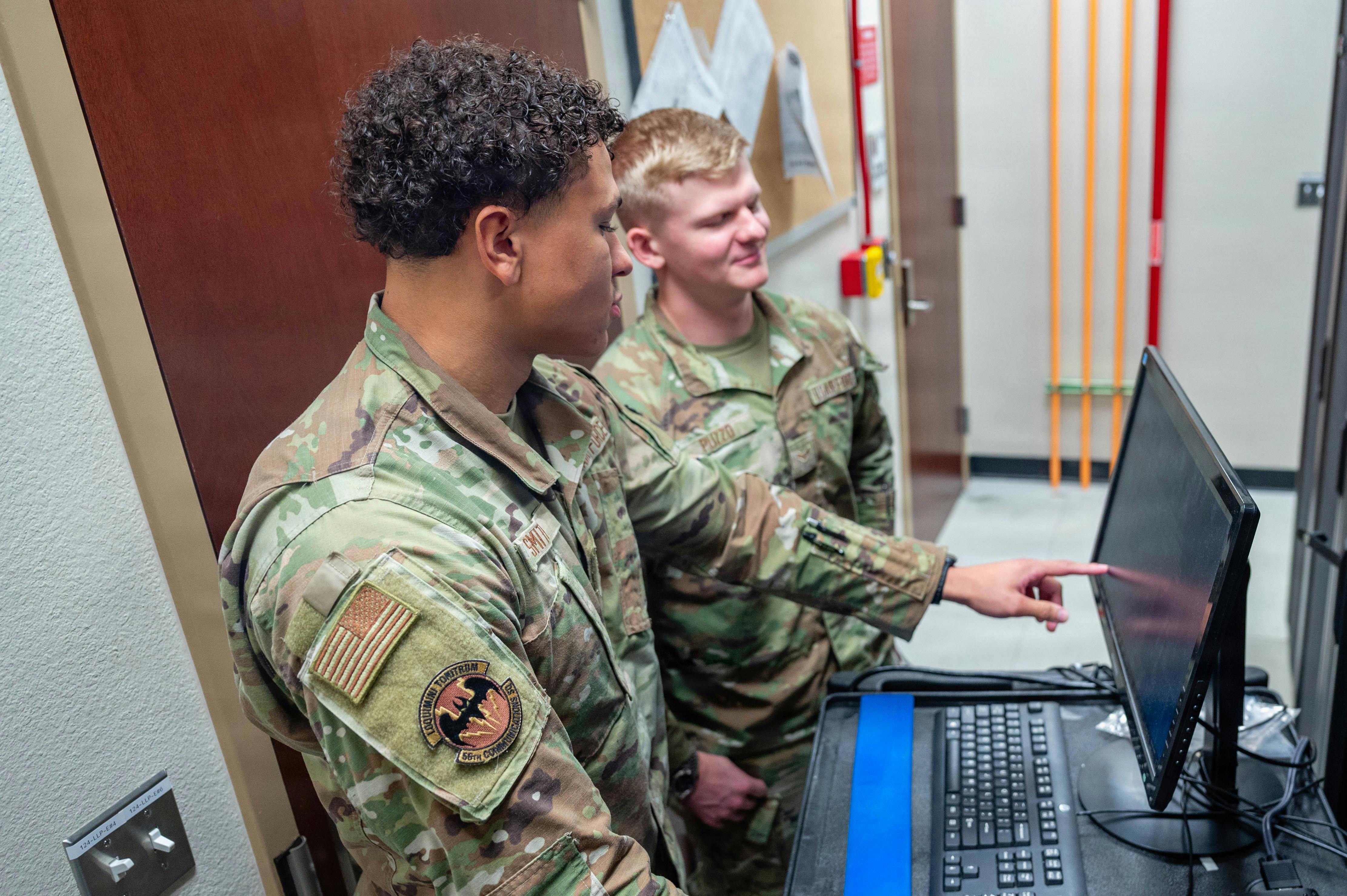 U.S. Air Force Airman 1st Class Devyn Smith (left), and Airman 1st Class Dominic Puzzo (right), both 56th Communications Squadron network systems operation technicians, work together to maintain a server. U.S. Air Force photo by Airman 1st Class Tekorey Watkins.